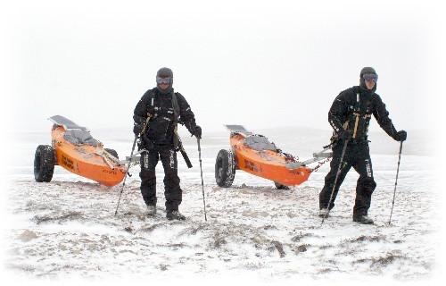 Chris and Clark hauling PACs towards camera along snow covered esker